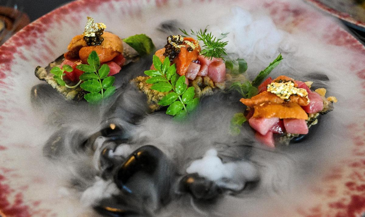 Uni, or sea urchin, with shiso and caviar comes with dry ice fog pouring off the rocks it’s served on at O-iza Japanese Cuisine in the River Park shopping center.
