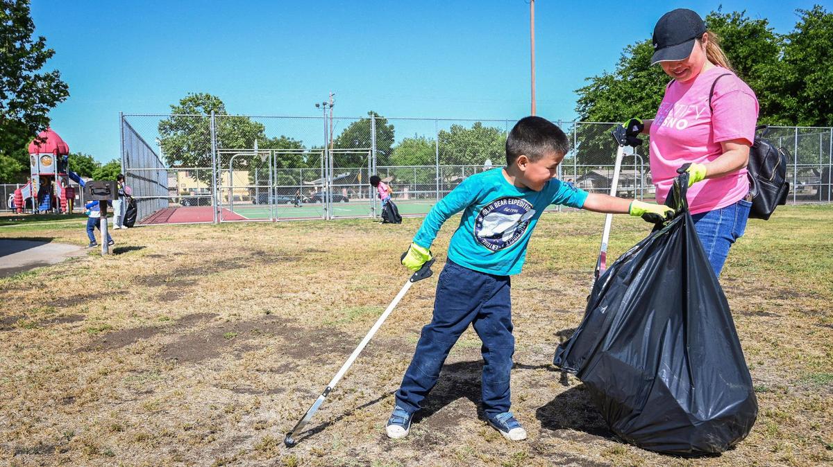 Kendrick Reyes, 6, of Fresno helps pick up trash with his mother, Maysia Lee, while participating in Beautify Fresno’s Great American Cleanup event at Fink-White Park in Fresno on Saturday, April 30, 2022.