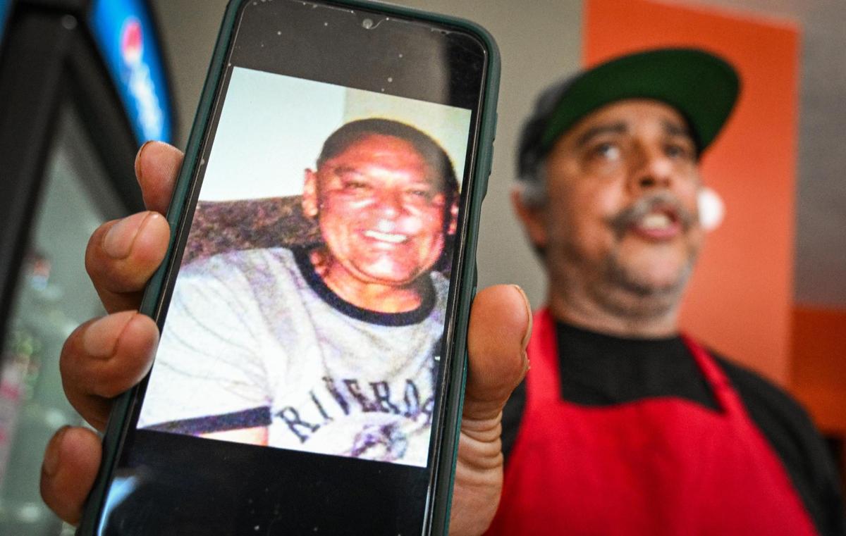 Bernard Paul Mendoza III holds up a photo of his father, Bernard “Ben” Mendoza, who inspired Bernard Mendoza III to pursue his dream of cooking and as well as the name of his restaurant, BenSmokin BBQ, on Wednesday, July 12, 2023.
