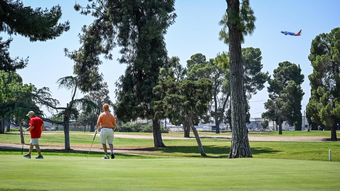 Golfers walk off the green as a commercial jet flies overhead at Airways Golf Course in Fresno on Thursday, May 1, 2025.