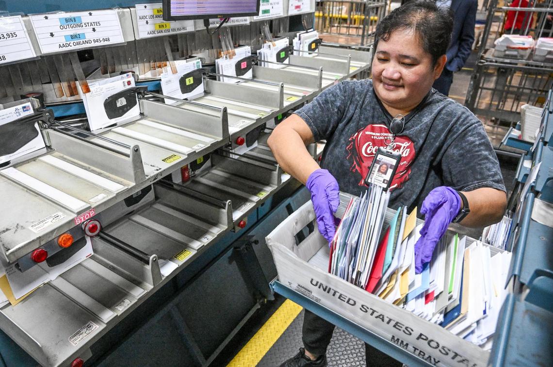 Grace Alberto gathers letter mail to be sorted at a United States Postal Service mail processing center in Fresno in December 2024. Mail delivery will not be affected by the federal government shutdown.