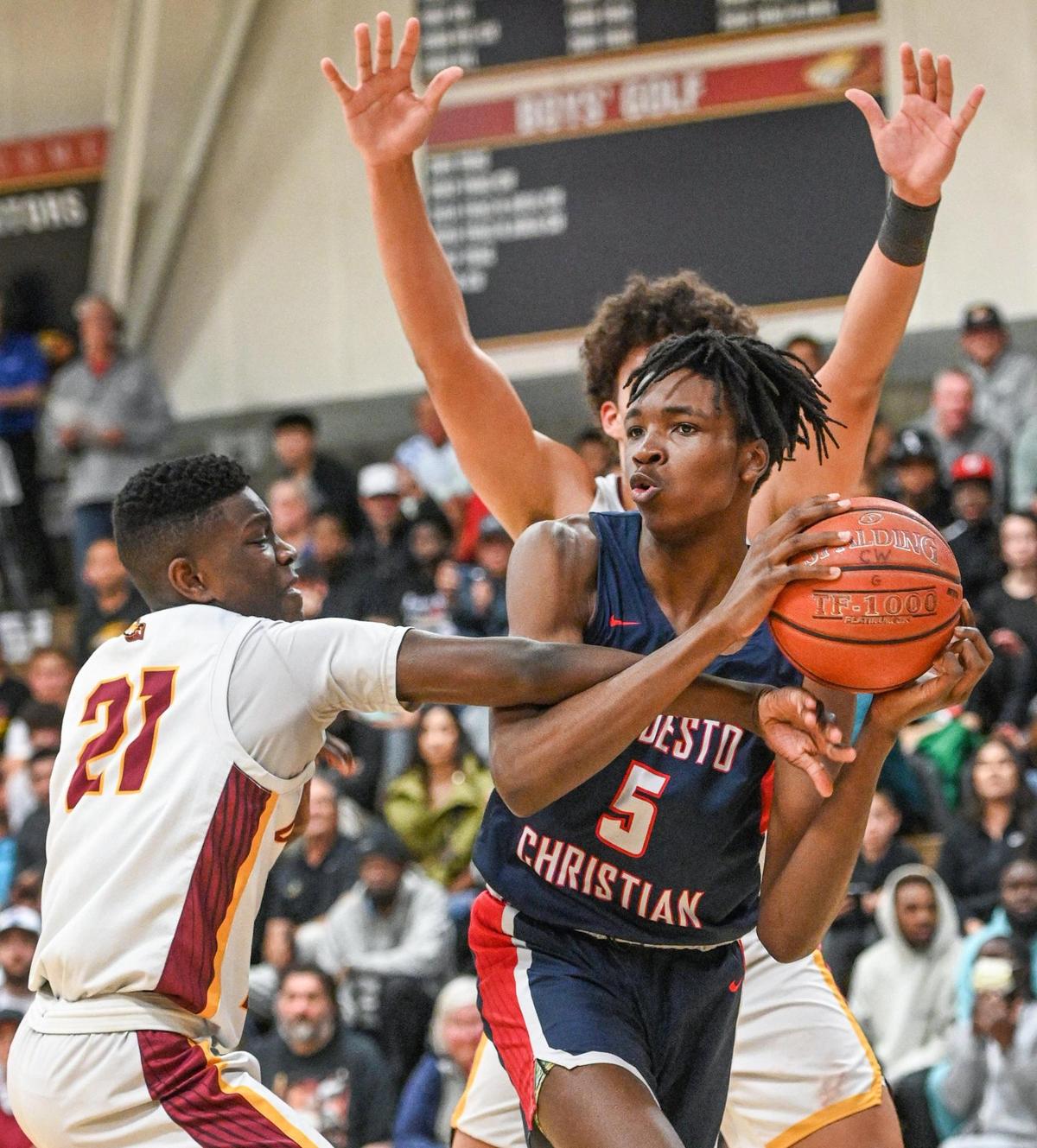 Clovis West’s DJ Stickman, left, reaches in as Modesto Christian (player unidentified, not on roster) grabs a rebound during their NorCal Open Division boys basketball semifinal at Clovis West on Saturday, March 5, 2022.