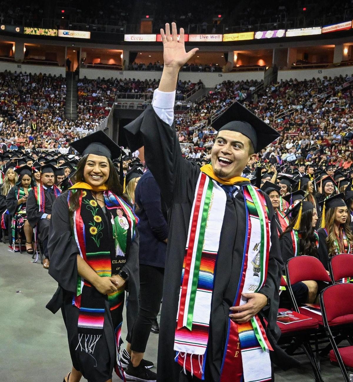 Graduating students wave to family and friends during the 46th annual Fresno State Chicano/Latino Commencement Ceremony held at the Save Mart Center on Saturday, May 21, 2022.