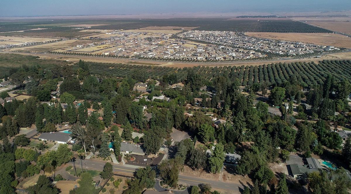 An aerial shot shows the Rolling Hills area of Madera (foreground) near Highway 41 and Avenue 11 and hundreds of new homes in the Riverstone development (background) on Monday, Oct. 14, 2019.