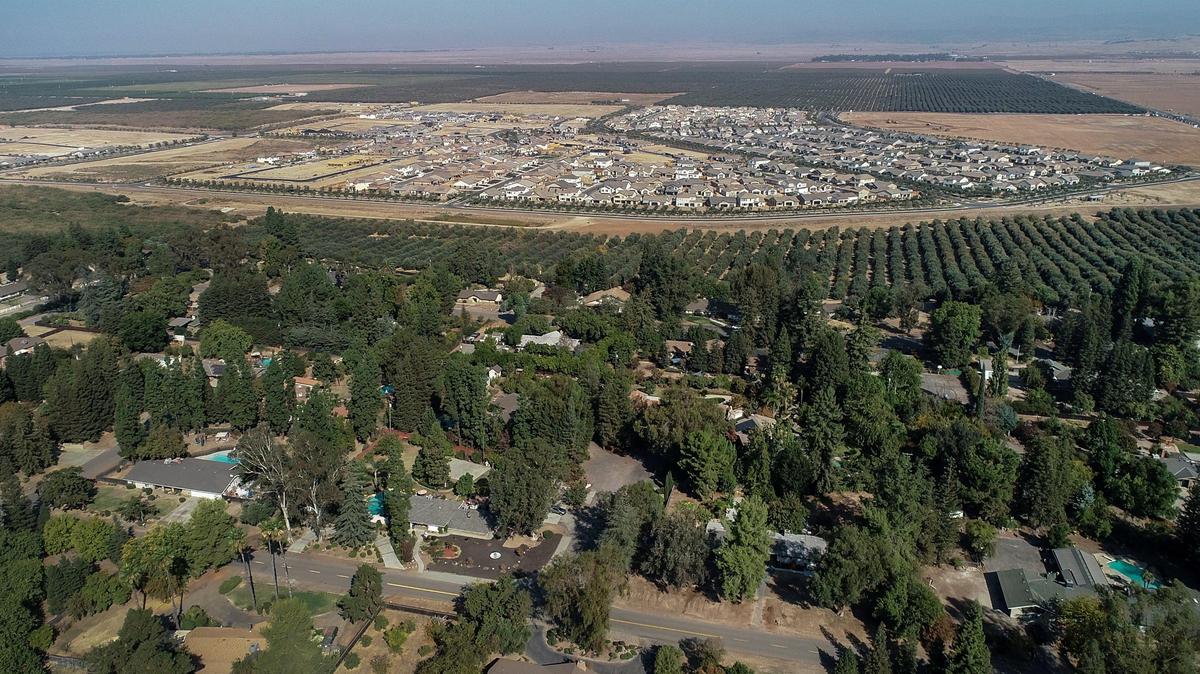 An aerial shot shows the Rolling Hills neighborhood of Madera County (foreground) near Highway 41 and Avenue 11 and hundreds of new homes in the Riverstone development (background) on Monday, Oct. 14, 2019.