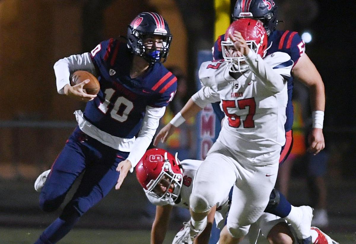 San Joaquin Memorial quarterback Carson Dean, left, scrambles pursued by Sanger’s defense Friday, Oct. 28, 2022 in Fresno. Memorial led 28-14 at halftime.