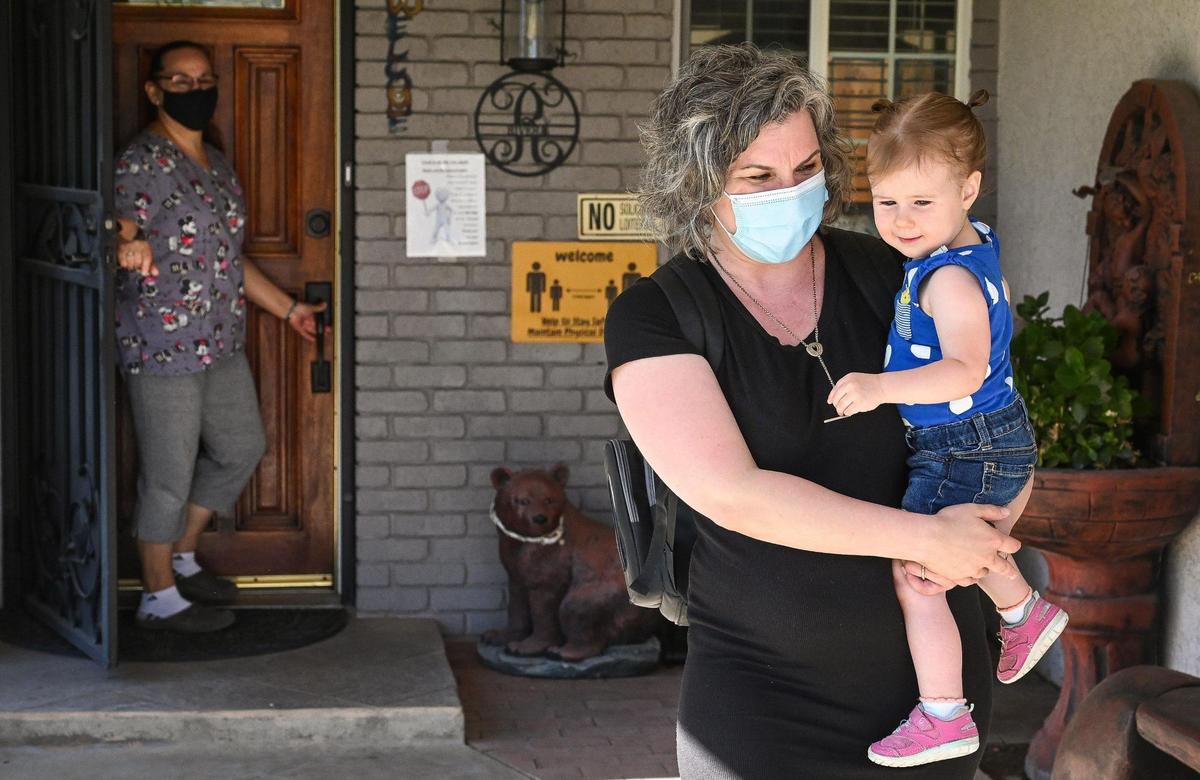 Amanda Tripp of Fresno carries her daughter Ellie, 2, after picking her up from her child care provider on Thursday, June 16, 2022. After a difficult search, Tripp was able to find the licensed child care provider when her original provider closed her business last year.