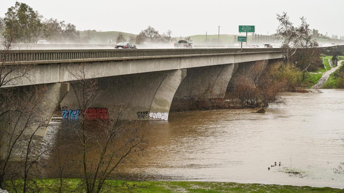 San Joaquin River water swells along the Highway 41 bridge between Fresno and Madera counties as rain continues during an atmospheric river storm event on Saturday, Jan. 14, 2023.