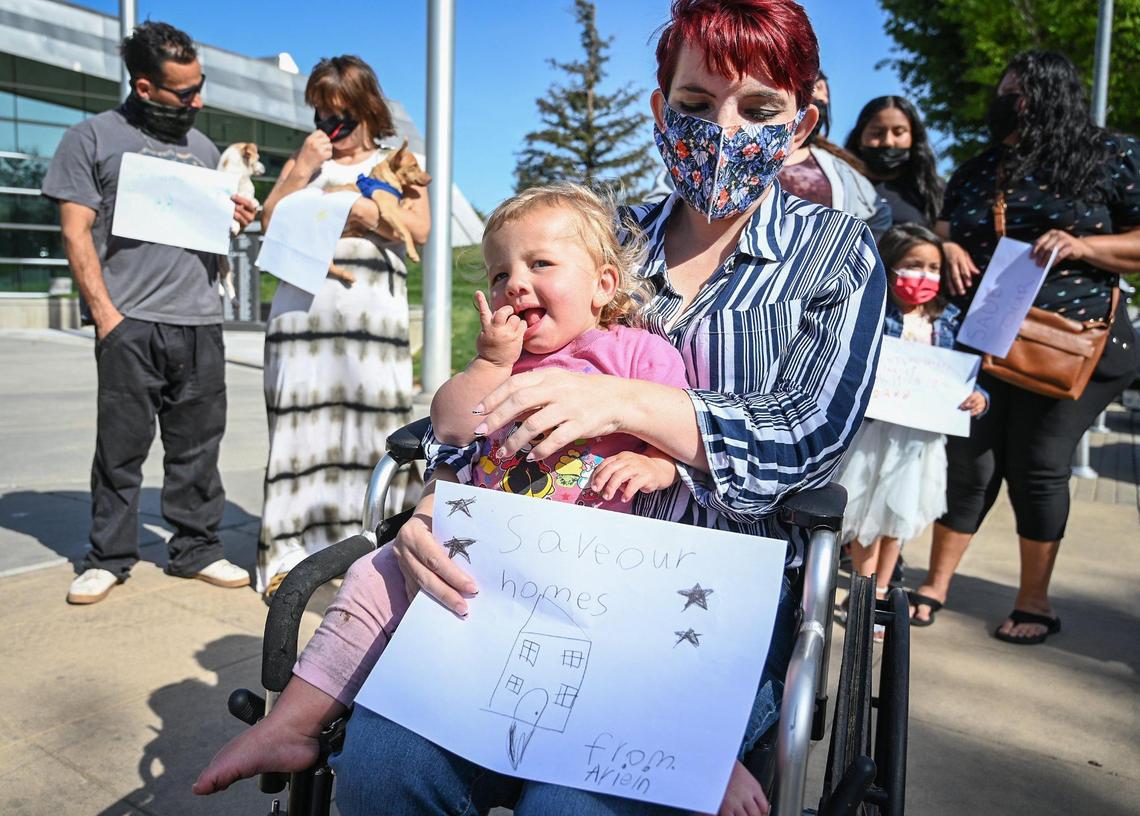 Trails End Mobile Home Park resident Heidi Phipps sits with her daughter Lucylle and a drawing from one of her neighbor kids before entering Fresno City Hall with other residents ask city leaders to help them block the sale of the park to Harmony Communities, on Tuesday, April 5, 2022.