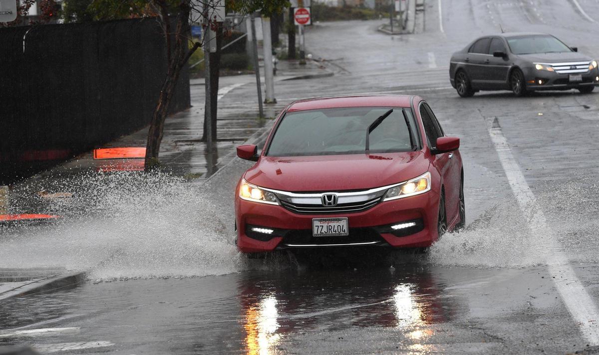 A car drives through a flooded street corner at Stanislaus and the 99 onramp during the storm Tuesday, Dec. 14, 2021.