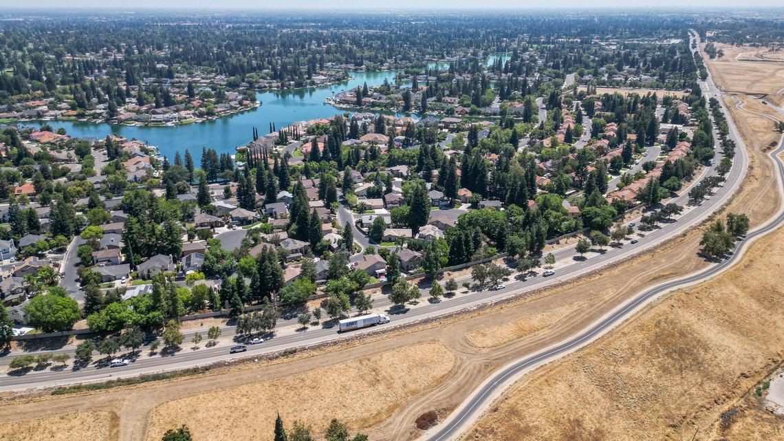 Traffic flows along Friant Road near Woodward Lake in north Fresno on Monday, Aug. 5, 2024. Several safety measures have been implemented along a dangerous section of Friant Road in north Fresno including high-visibility crosswalks, reflective signal backplates, and no right turn on red signs.