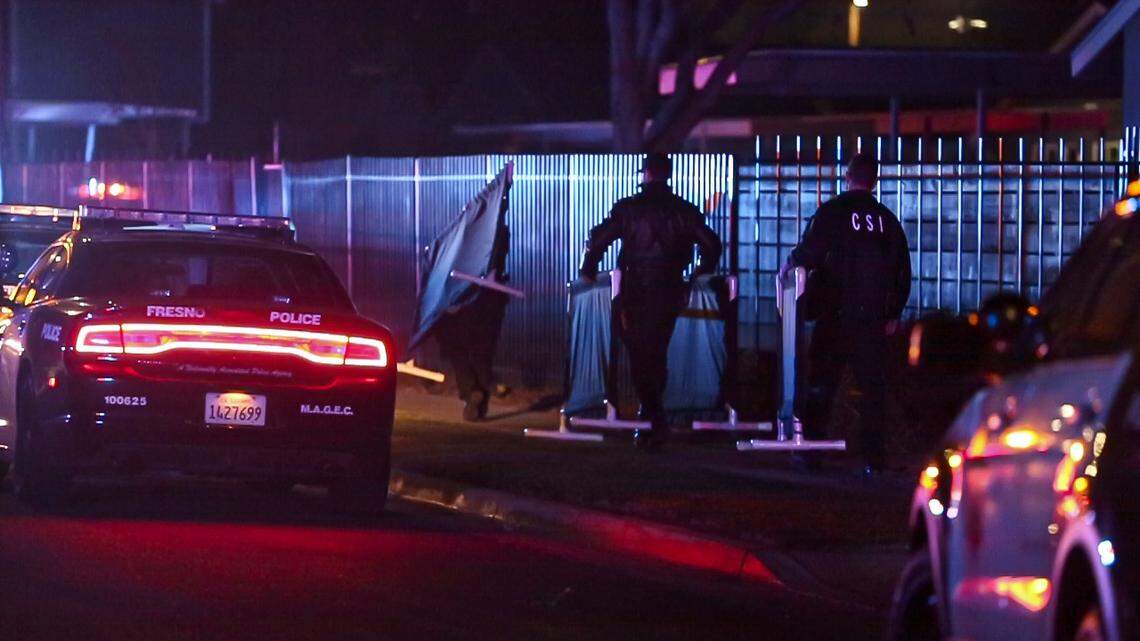 Officers carry covering to cover the body of two people killed in a shooting inside an apartment complex in southwest Fresno, Sunday Feb. 6, 2022.