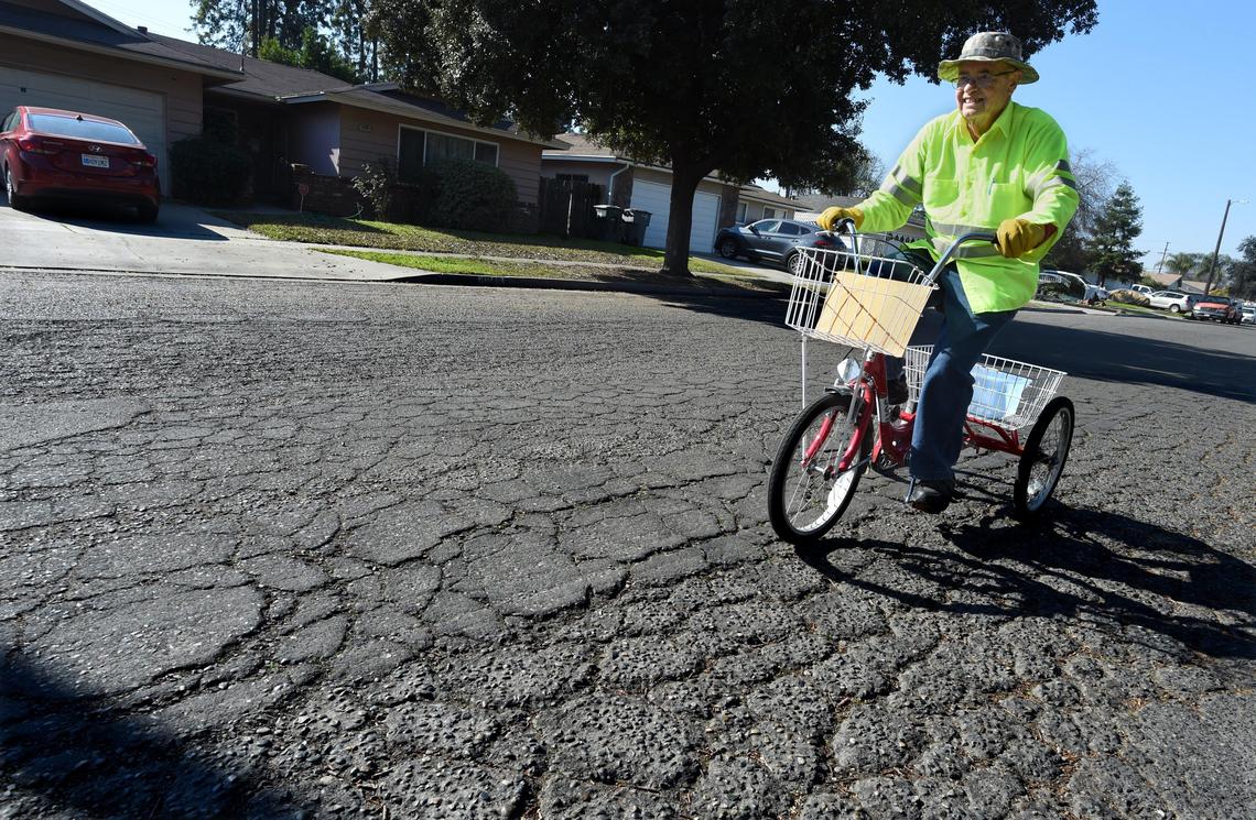 78-year-old Garrett Wimer steers his tricycle over the broken asphalt street surface of East Cambridge Avenue, for a teeth-jarring ride, east of Chestnut Avenue, last paved 50 years ago, and said to be one of the worst streets in Fresno.