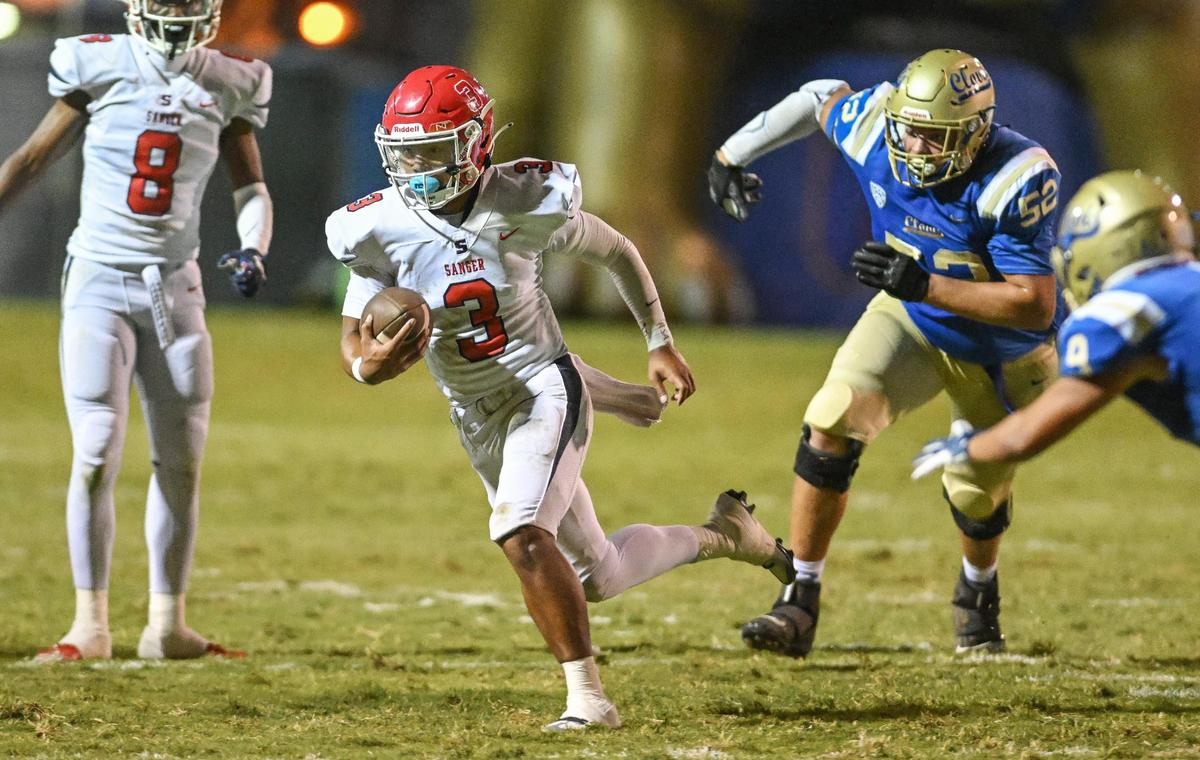 Sanger quarterback Jaden Chanthalangsy, center, takes the ball up the middle on a keeper against Clovis during their game at Lamonica Stadium in Clovis on Friday, Aug. 25, 2023.