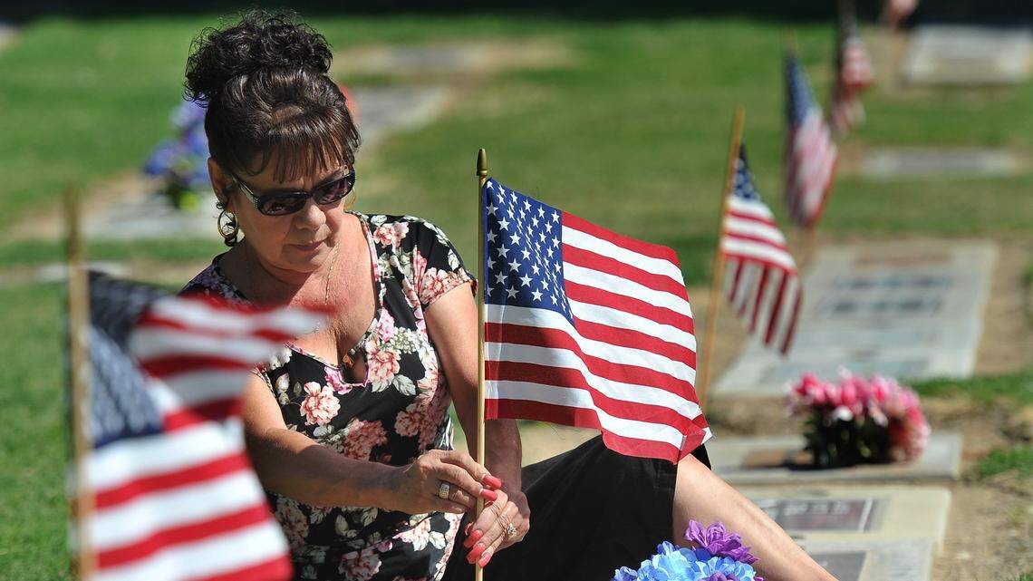 Loretta Reyna places a flag on the grave of her father, Korean War Army veteran Loman Orum, at the Clovis Cemetery on on Memorial Day, May 28, 2018.
