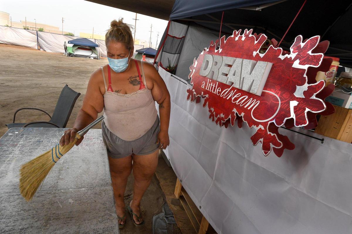 Kathy Miranda, a resident of a homeless encampment named Dream Camp, brushes off a table at the communal kitchen, Thursday, Aug. 20, 2020. Fresno homeless advocate Dez Martinez set up the camp with community donations and help. She was frustrated by the lack of safety on Santa Clara Street.