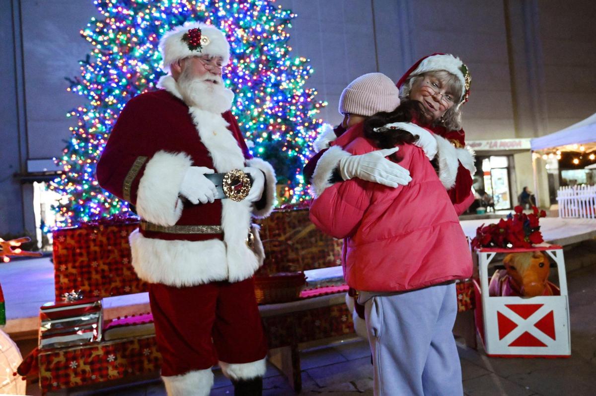 A child receives a hug from Mrs Claus as Santa stands by during Downtown Fresno Partnership’s annual Christmas Tree Lighting ceremony at Mariposa Plaza on Friday.