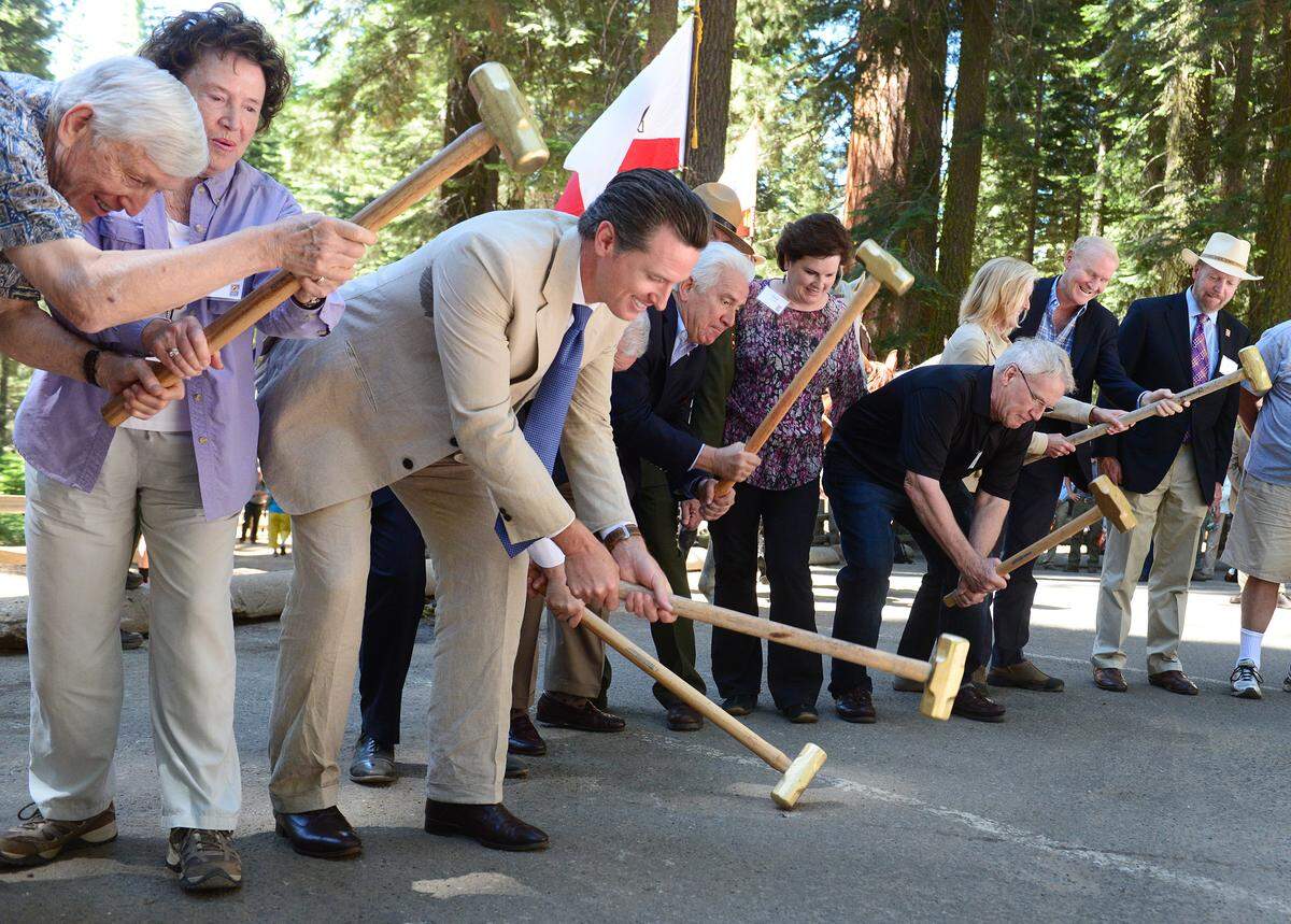 Dignitaries including Lt. Gov. Gavin Newsom, third from left, swing sledgehammers onto an asphalt parking lot during a ceremonial groundbreaking for the restoration of the Mariposa Grove of Giant Sequoias on June 30, 2014.