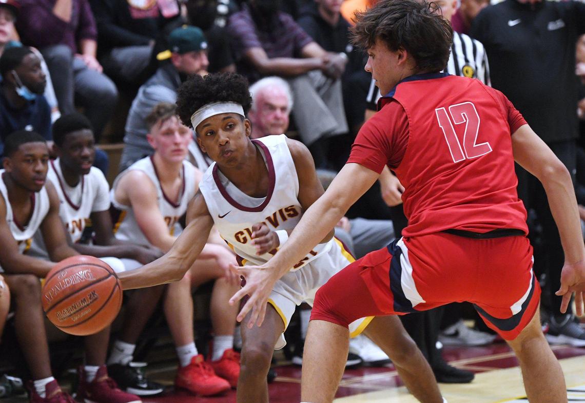 Clovis West’s Trey Carr, left, passes around San Joaquin Memorial’s Jack Wade, right, in Open Division action Saturday, Feb. 19, 2022 in Fresno. Clovis West defeated San Joaquin Memorial 83-69.