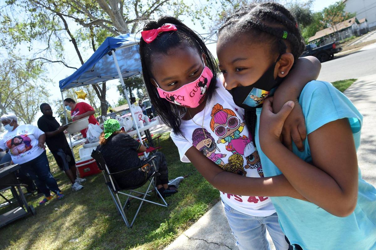 Tia Glenn, 5, center, and Ariane Beard, 6, share a hug during Resurrection Day Celebration held by The Free AME Ministries, on Saturday, April 3, 2021, in Fresno.