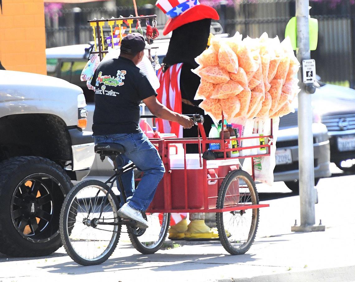 A Fresno street vendor works the busy intersection of Tulare and Cedar avenues, March 31, 2021.