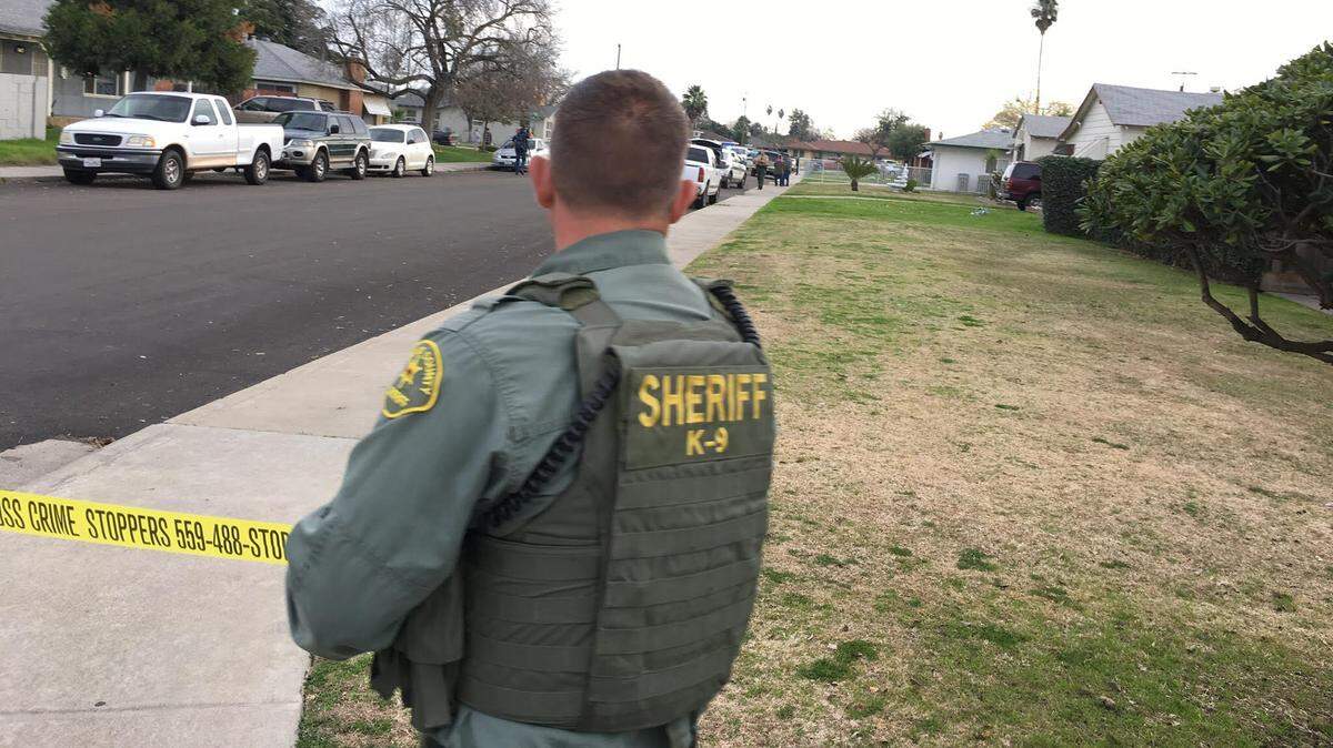 A deputy with the Fresno County Sheriff’s Office blocks off the road Friday after an officer-involved shooting with a suspect who reportedly threatened to kill a woman.