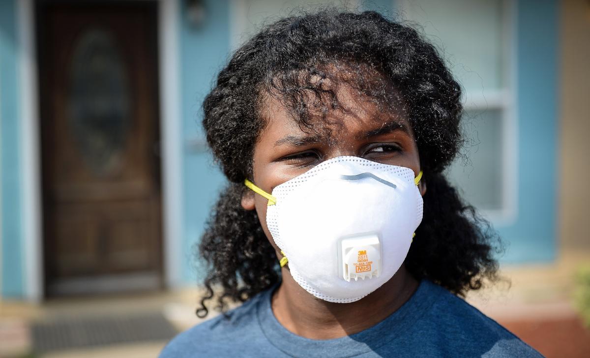 Dyami Hunt, 14, who has asthma and is recovering from walking pneumonia, wears a mask to filter the smokey air while spending time outdoors near his home in Fresno on Thursday, Aug. 9, 2018. 