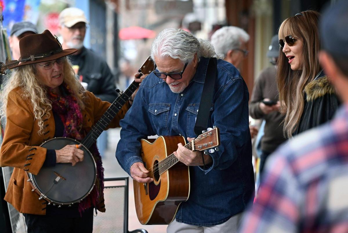 Musicians gather outside outside Scoops, Soups & More on Pollasky Avenue with Melvin Mason, known as Kuzzin Mel, playing music in Old Town Clovis Thursday, Feb. 20, 2025.