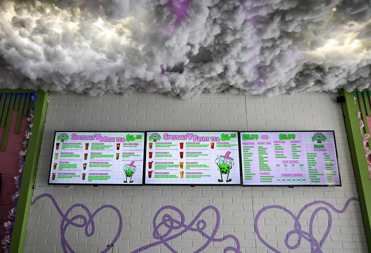 The K-pop-themed boba tea menu at Bubble Pop Tea in Fresno sits below a cloud of cotton on the ceiling and above a purple script mural that covers the wall of the shop.