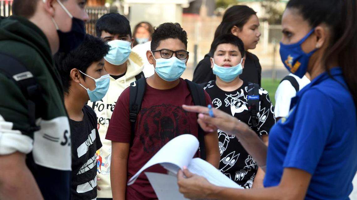 Tehipite Middle School 8th grader Matthew Contreras, center, with other students, listen to instructions from staff member Sukhi Nagra as they enter campus for the first day of school, Thursday, Aug. 12, 2021.