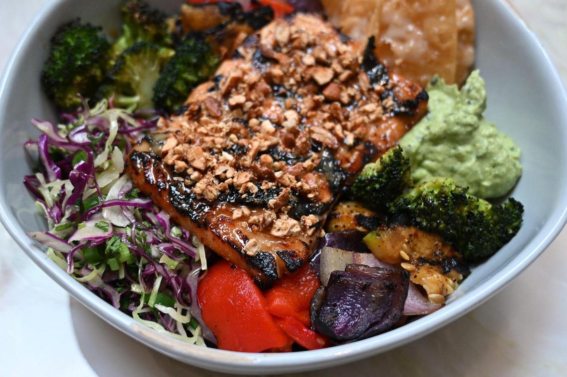 A miso salmon bowl featuring marinated salmon, squash, broccoli, cashew sauce, candied cashews, wontons, a soy glaze and avocado wasabi is one of many lunch offerings at Otherside Cafe.