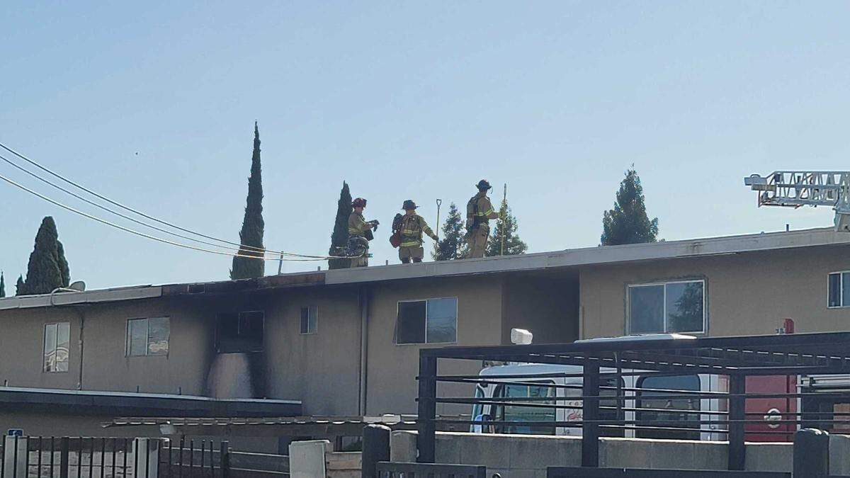Firefighters check the roof of the Cambridge Court Apartments in central Fresno after a fire damaged two units on Monday, April 4, 2022.
