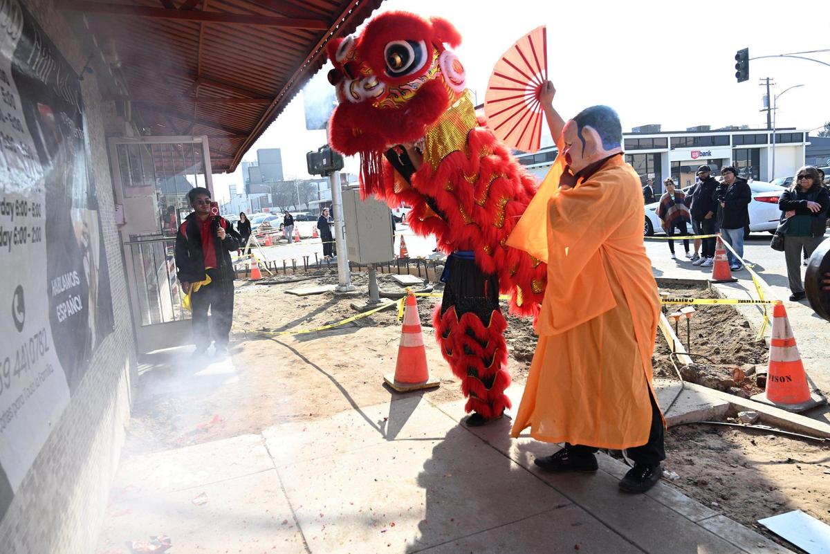 The smoke from firecrackers is seen to the left as the Chinese New Year Lion Dancers prepare to enter a business Saturday morning, Jan. 25, 2025 in Fresno’s Chinatown.