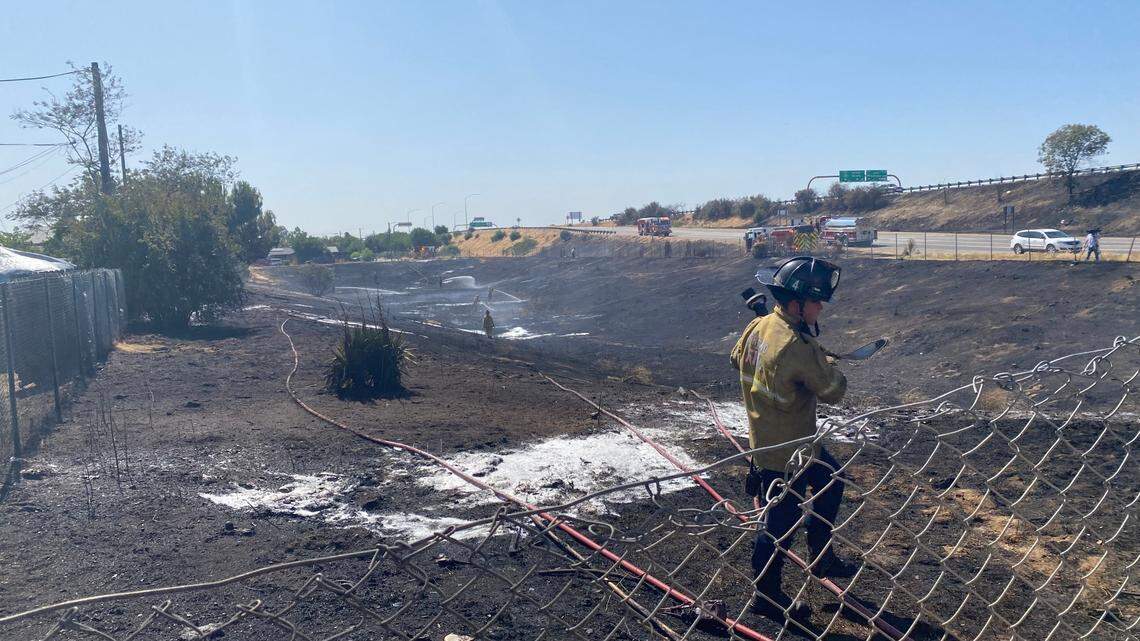 A firefighter pours water after a grass fire sparked up Saturday, June 21, 2025 in Fresno, California.