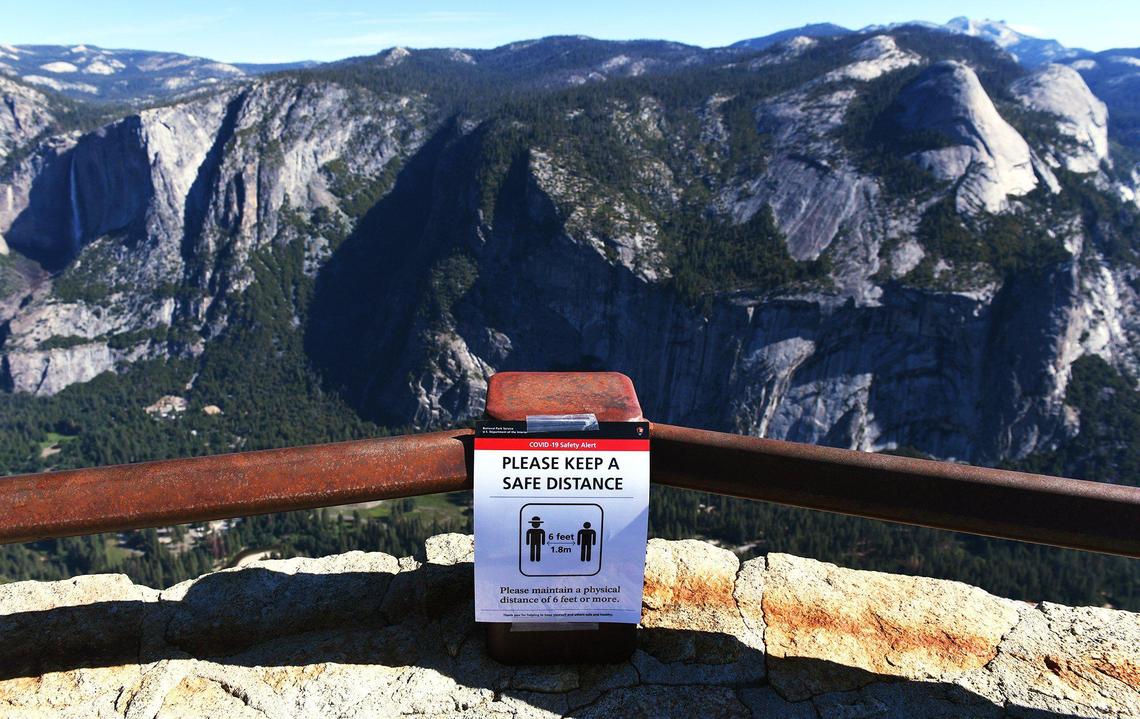 A reminder to keep social distancing can be seen at Glacier Point overlooking Yosemite Valley as the park re-opens after closure due to coronavirus Thursday morning, June 11, 2020.