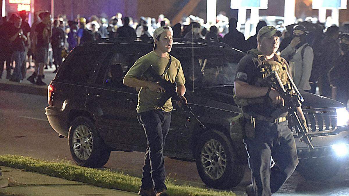 Kyle Rittenhouse, left, with backwards cap, walks along Sheridan Road in Kenosha, Wis., Tuesday, Aug. 25, 2020, with another armed civilian.