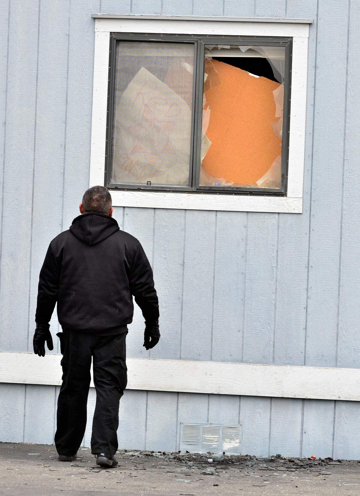 A security guard looks at a broken window, through which a burning log was thrown in, during an occupation of the Coarsegold tribal offices of the Picayune Rancheria of the Chukchansi Indians in February 2012.