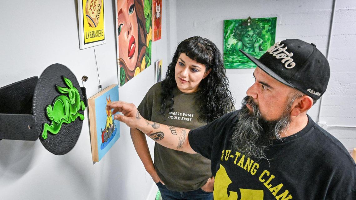 Roeski Doeski, and Jennie Graham, co-owners of Hella Fresno and Hearts of Downtown Workshop Studio in downtown Fresno, look over a piece of interactive art while setting up an ArtHop gallery at the studio on Wednesday, March 6, 2025.