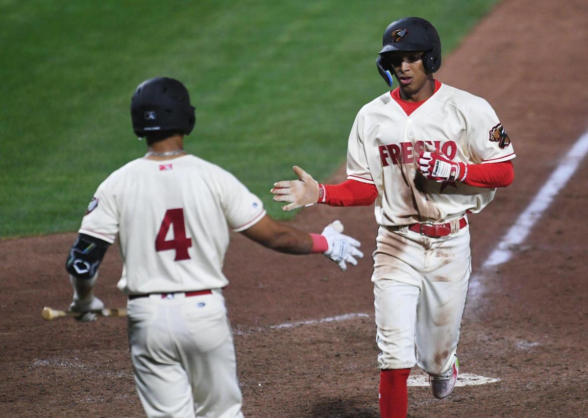Fresno Grizzlies Andy Perez, right, scores a run in the 8th inning in the 2023 home opener against the Stockton Ports Tuesday, April 11, 2023 in Fresno.