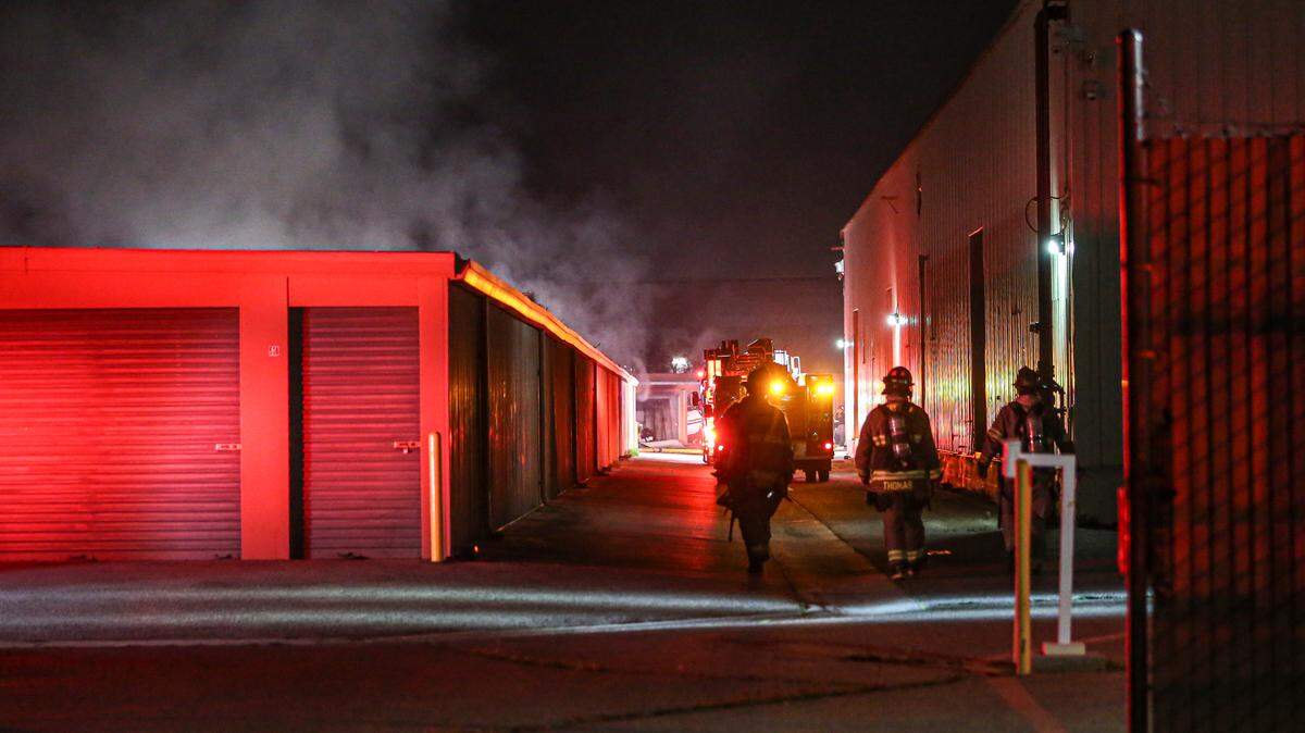 Firefighters walk to the back of a storage facility as 7 units burn in southeast Fresno on Monday, Jan. 17, 2022.