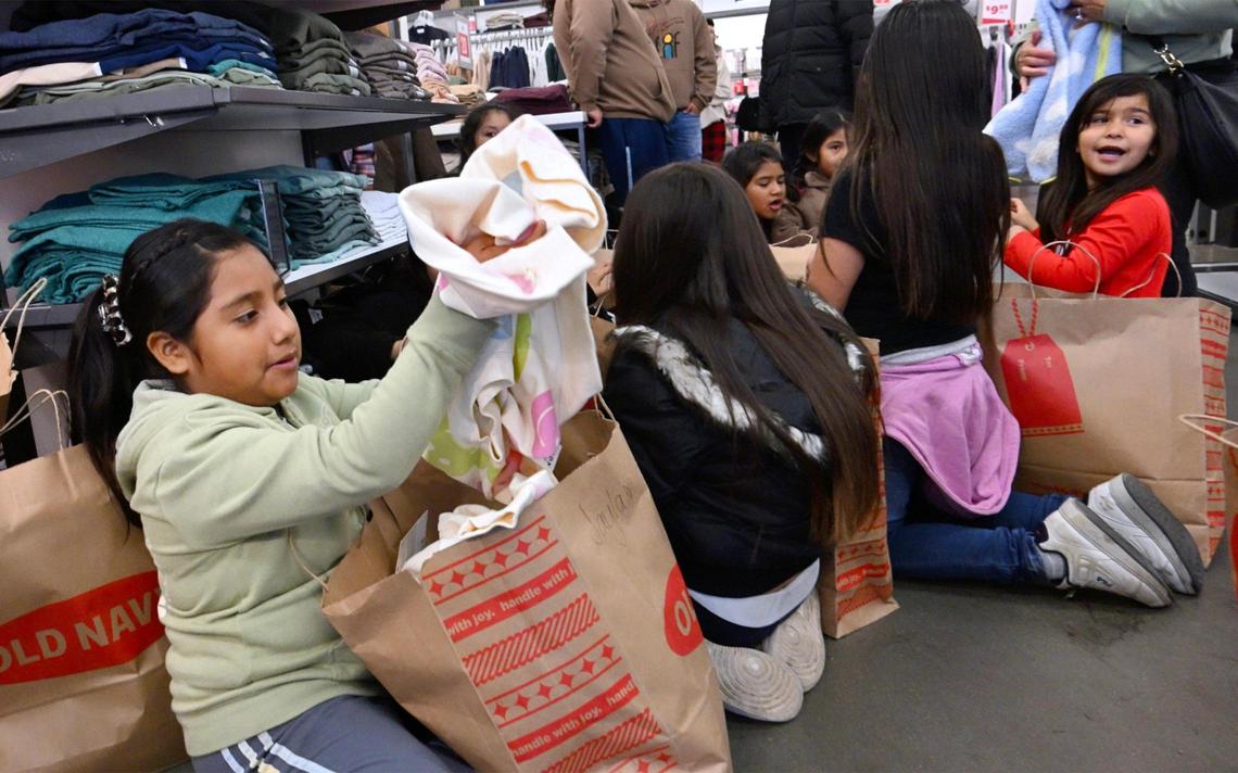 Children gather to share the clothing they purchased after a shopping spree organized by Live Again Fresno at Old Navy Monday morning, Dec. 18, 2023 in Fresno.