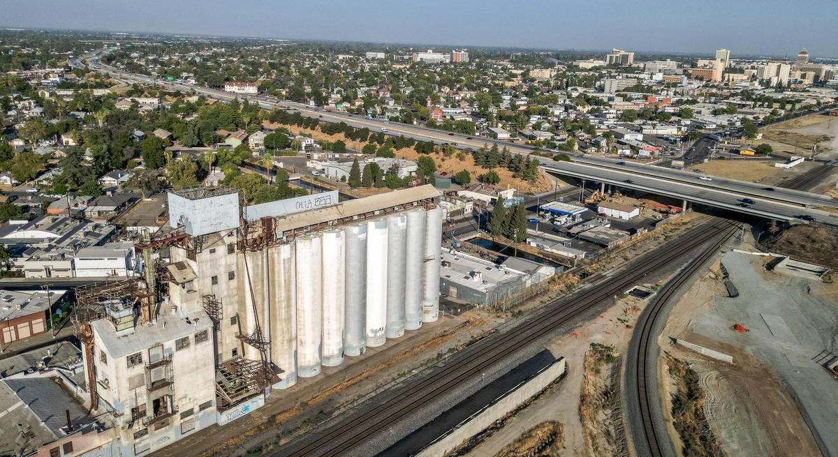 The former Zacky Farms feed silos, lower left, stand near Highway 180 and downtown Fresno on Wednesday, Aug. 28, 2024. Producers Dairy, which now owns the land the silos are on, is planning on demolishing them.