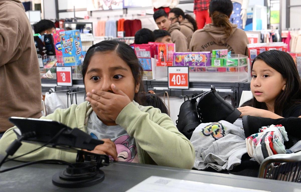 Niños de Live Again Fresno reaccionan mientras la ropa es revisada en las cajas registradoras durante una compra en Old Navy, la mañana del lunes 18 de diciembre de 2023, en Fresno.