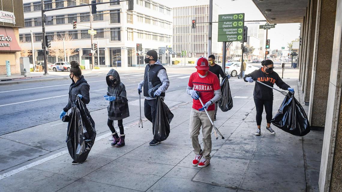 Volunteers help pick up trash on Fresno Street at Fulton Street in downtown Fresno during one of two cleanup events as a part of Mayor Jerry Dyer’s new initiative, Beautify Fresno, to celebrate the National Day of Service on Martin Luther King Jr. Day, Monday, Jan. 18, 2021. About 200 volunteers signed up for the event to pick up trash in the Fulton District and the Lowell District to honor the legacy of the late Reverend King. On Martin Luther King Jr. Day residents are encouraged to use the holiday as “a day on, not a day off” and look for ways to volunteer to make their communities better.