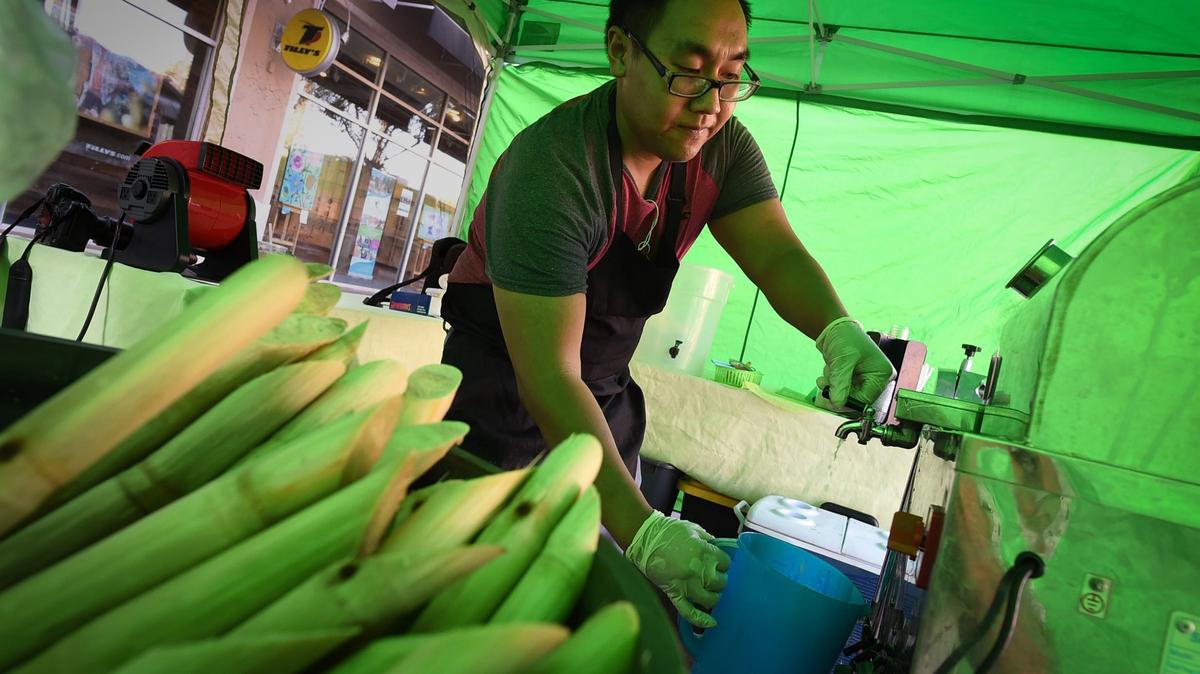 H. Ho, owner of H’s Sugar Cane Cafe, draws freshly squeezed sugar cane juice for cold drinks at the River Park Farmers Market’s Gourmet Way. As of several days ago, all Asian food sellers were told they could not sell at the farmers market anymore.