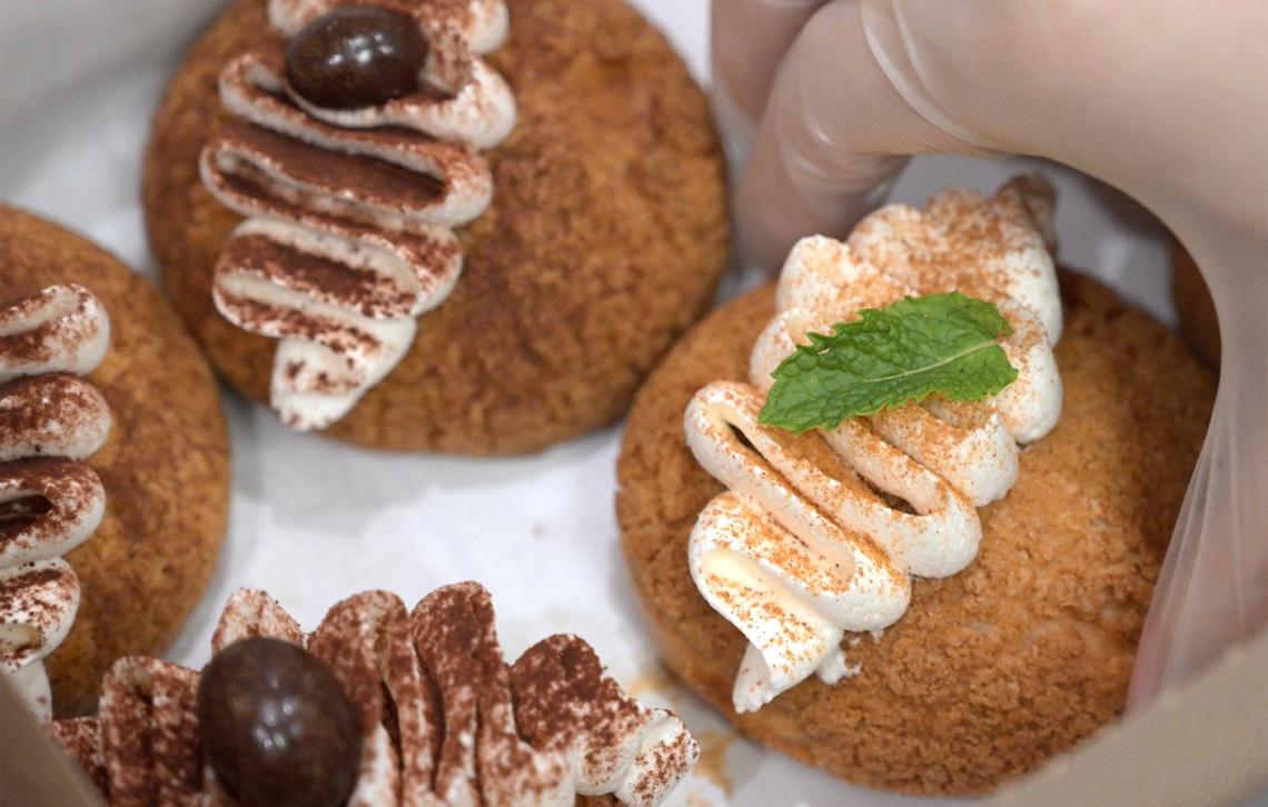 Selena Le selects a Thai tea cream puff, right, with coffee cream puffs to the left, both supplied from Culture Bakehouse, for her new restaurant Springly. It serves Vietnamese-inspired food and pastries with a partnership serving coffee through Chase Benedettis’s Noc Box Coffee Studio.