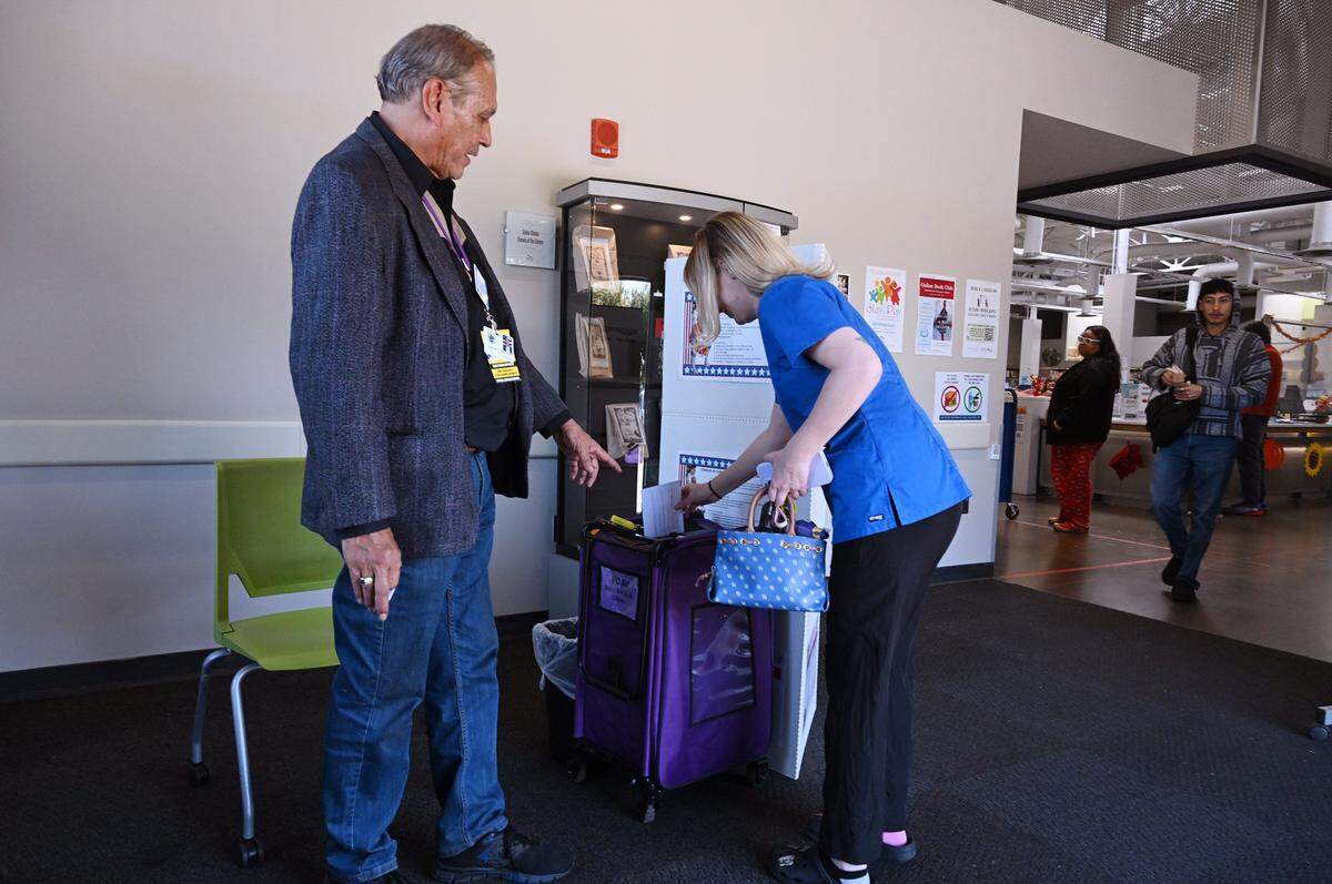 Election coordinator Arthur Gonzales, left, helps direct Calista Font at the Betty Rodriguez Public Library voting center Tuesday, Nov. 4, 2025 in Fresno. Font said voting in person made her feel as if she was a real part of voting for the state.