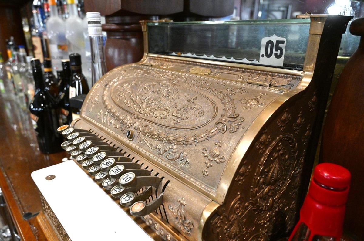 A vintage cash register can be seen behind the bar at Cosmopolitan Tavern & Italian Grill, located in downtown Fresno. Photographed Friday, Oct. 25, 2024.