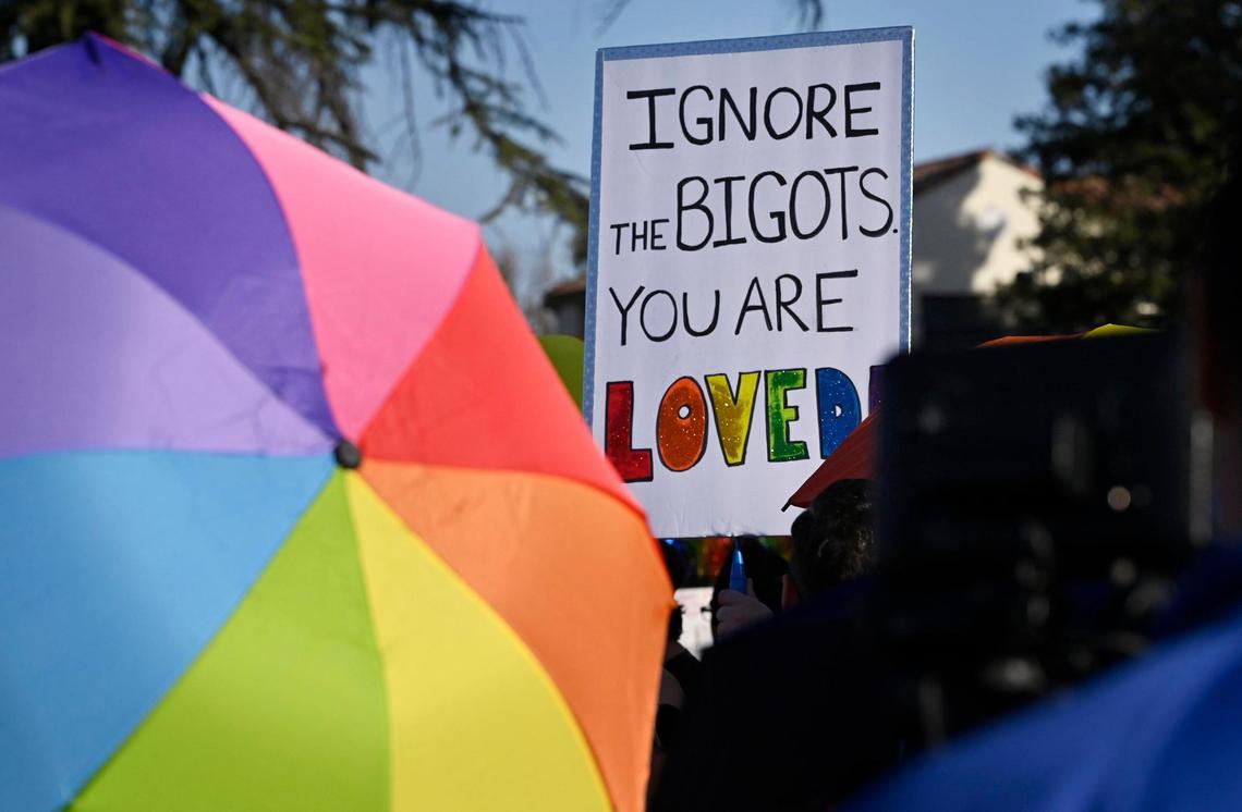 Signs are held aloft as a coalition of LGBTQ+ organizations and supporters, headed by LGBT+ Fresno, held a counter-protest outside Roosevelt Hgh School featuring rainbow-themed umbrellas as symbolic shields against a group from Westboro Baptist Church Monday, Oct. 28, 2024, Fresno.