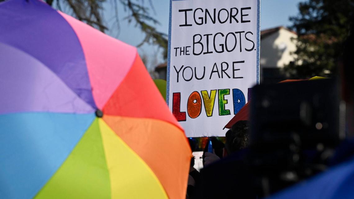 Signs are held aloft as a coalition of LGBTQ+ organizations and supporters, headed by LGBT+ Fresno, held a counter-protest outside Roosevelt High School featuring rainbow-themed umbrellas as symbolic shields against a group from Westboro Baptist Church Monday, Oct. 28, 2024, Fresno.